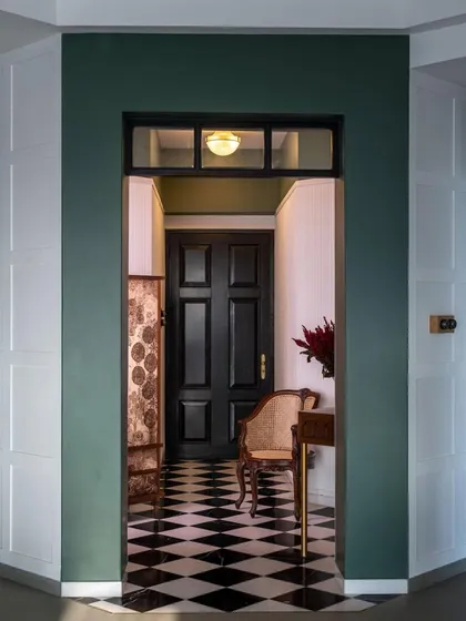 I believe in making a strong first impression. The entrance of the 'Inde Blue' home uses a bold, deep green to create a jewel-box effect, drawing you into the space. The classic checkered flooring and paneled walls are a nod to timeless design, creating a dialogue between the old and the new from the moment you step inside.