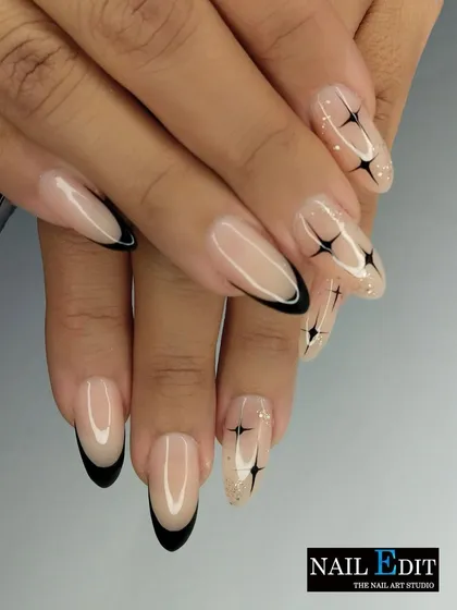 A modern twist on the classic French manicure. This design features sharp, black French tips on a clean, natural base, accented with minimalist black starbursts and a sprinkle of glitter for a chic and edgy look on almond-shaped nails.