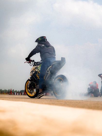 A rider performs a burnout on a KTM Duke, creating a massive cloud of smoke. This raw display of power is a staple of our stunt shows.