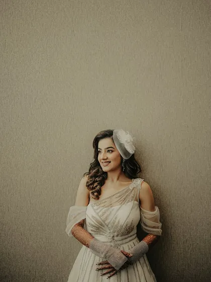A simple and elegant bridal portrait. The minimalist background puts all the focus on the bride, her beautiful smile, and her chic white gown with a fascinator.
