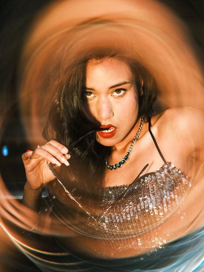 A close-up, expressive portrait of a woman, again using the warp filter to create a swirling light effect. Her direct gaze and pose create a bold and captivating image.