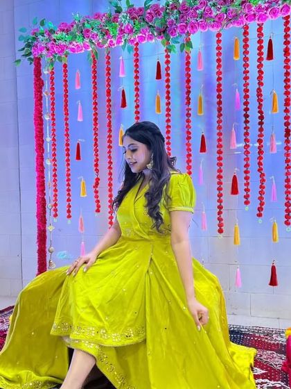 A simple yet elegant Mehndi backdrop with hanging tassels and floral strings, perfect for intimate home functions.