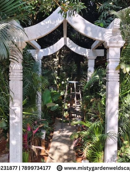 The completed stone arch, standing as a beautiful gateway amidst the dense foliage of the garden.
