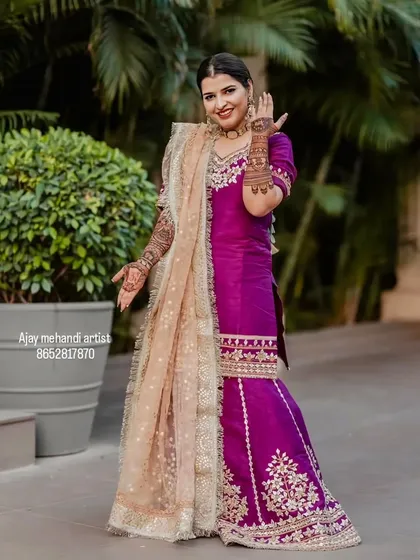 A client posing gracefully in her beautiful outfit, with her hands decorated with my mehndi art.