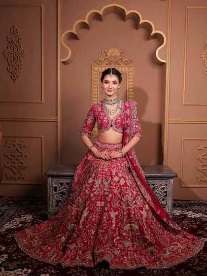 A full-length view of a bride looking absolutely regal in her red Jayanti Reddy lehenga. The makeup is designed to be flawless from every angle, ensuring she looks and feels like royalty on her big day.