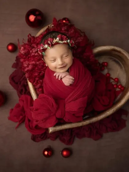 Another angle of this joyful Christmas baby, showing her sweet smile and cozy red wrap. These holiday themed sessions are a wonderful way to create memories for your family's greeting cards.