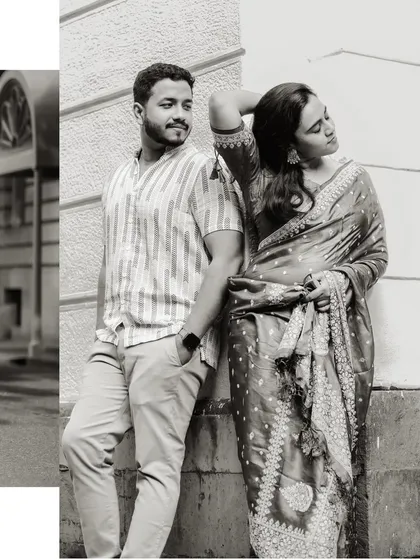 A stylish black and white portrait against a simple wall. The pose is relaxed and confident, showcasing their chemistry and the classic beauty of monochrome.