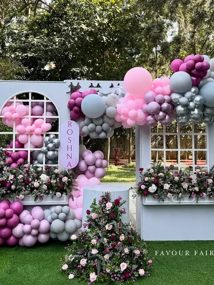 A whimsical bridal shower setup we designed, combining soft pink and grey balloons with beautiful fresh flowers. The custom window-pane backdrop and floral arrangements created a picture-perfect spot for the bride-to-be.