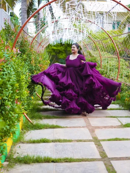 A joyful, twirling shot of the bride in her flowing purple gown. This photo captures her happiness and the beauty of the dress in a garden pathway.