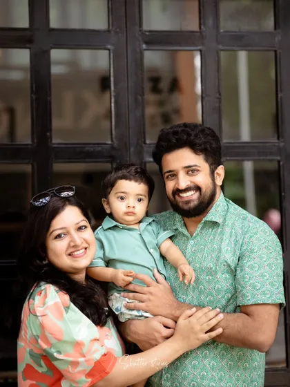 A classic family portrait against a dark wooden door, with everyone smiling happily.