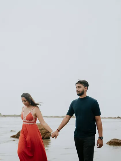 A couple walks hand-in-hand along the shoreline, a classic and romantic scene for any pre-wedding album.