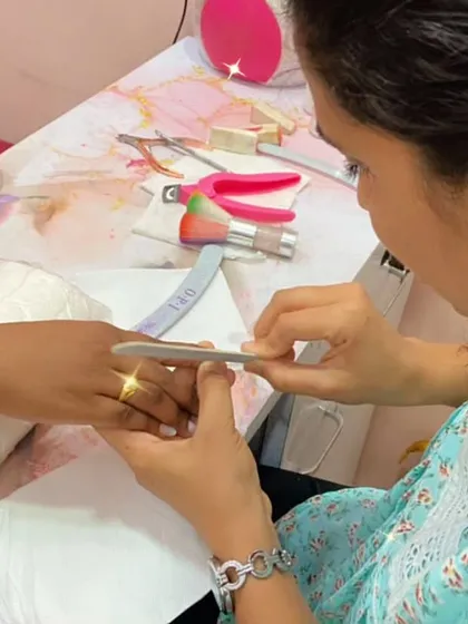 A student practices filing a client's nails, ensuring a smooth and even shape before applying polish.