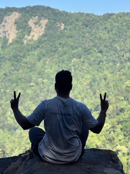 A trekker in a meditative pose, enjoying the peace and quiet of the Narasimha Parvatha viewpoint.