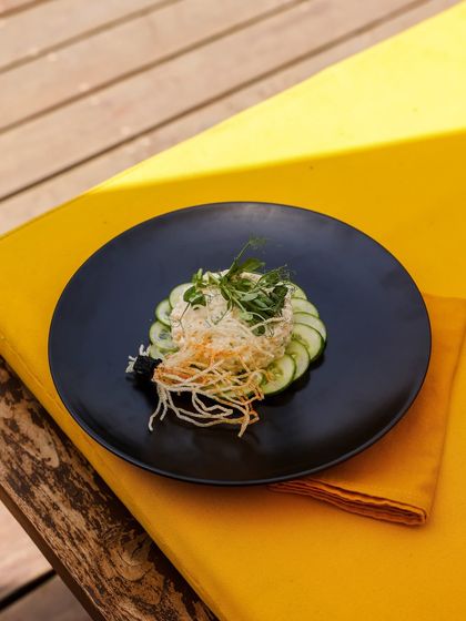 A light and refreshing cucumber and noodle salad, served on a bright yellow lounger cushion.