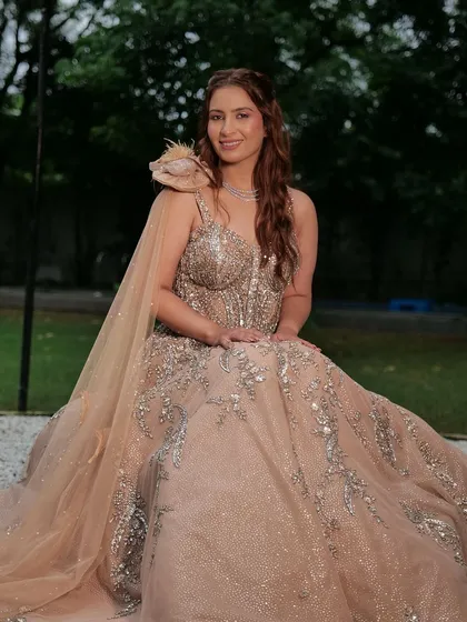 This wedding season, wear designer without disturbing your budget. A client looks stunning in a beige ball gown with a feathered shoulder detail, available for rent.