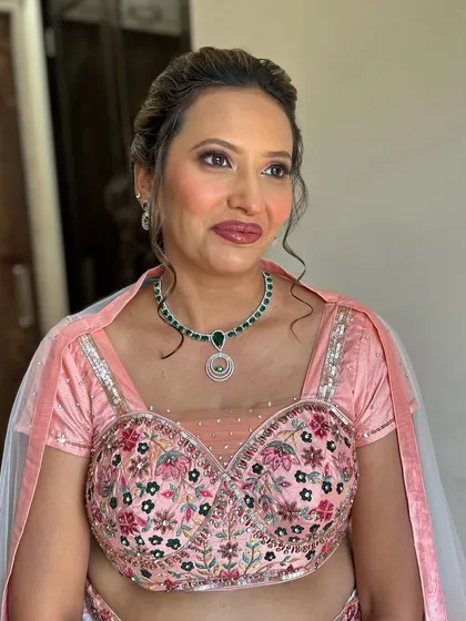 A beautiful mature client in a soft pink lehenga. The makeup is elegant and enhances her features, with a focus on her eyes.