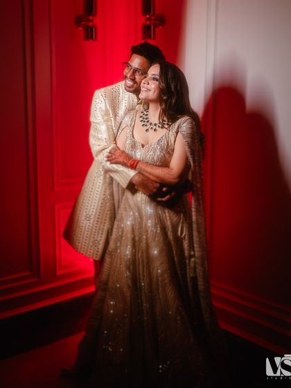 A happy, candid embrace against a bold red background. This shot captures the joy and passion of Archana and Akhil's celebration.