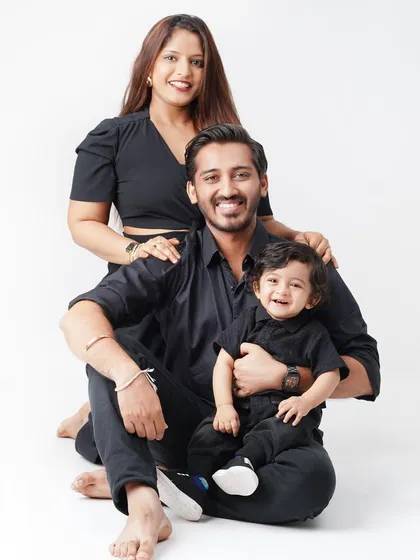 A stylish family portrait with everyone dressed in black, seated together against a white studio background, creating a modern and timeless look.