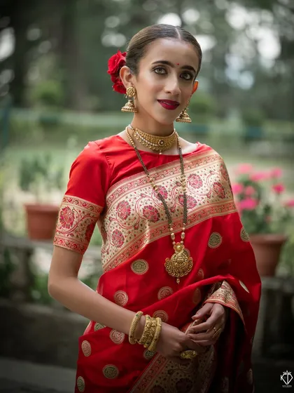 An elegant portrait of the model in a red saree, her pose highlighting the long gold necklace.