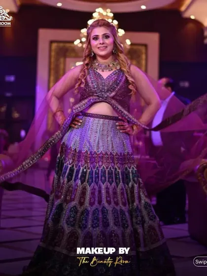 A full-length shot showcasing a complete engagement look. The client's hair is styled in soft waves that complement her intricate lehenga, creating a cohesive and stunning ensemble.