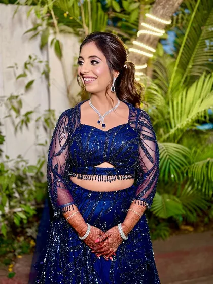 A full-length shot of the bride in her navy blue sequin lehenga. The makeup is glamorous and party-ready.