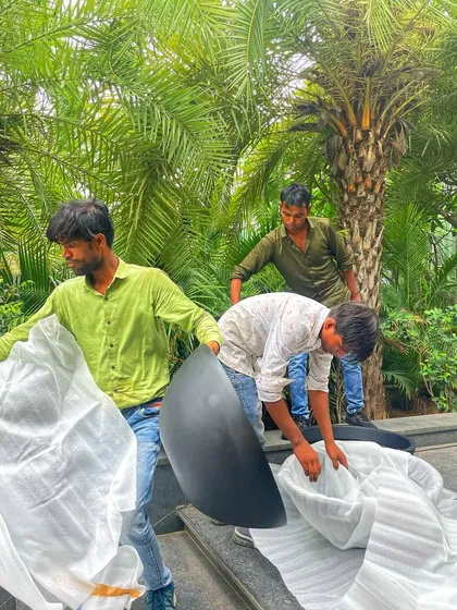 The setup process involves careful handling and placement. Here, my team is unwrapping and preparing the planters for the outdoor scenes of 'Call Me Bae'.