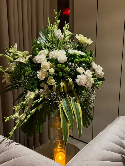 A lush arrangement of white lilies, carnations, and other blooms. We use generous, high quality floral arrangements to make a statement and fill a space with beauty and fragrance.