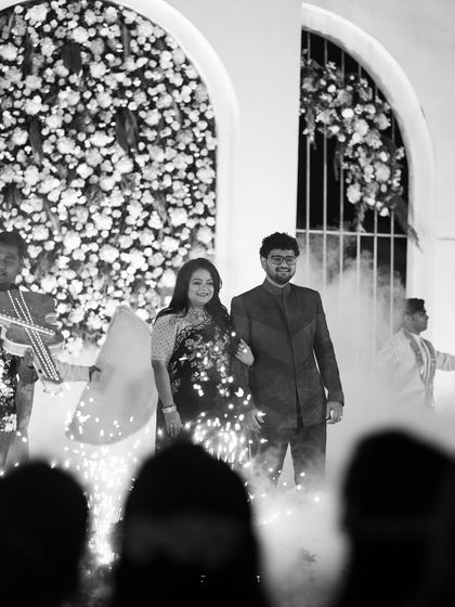 The couple's grand entrance at their reception, with sparklers lighting up their path and highlighting their glamorous outfits.