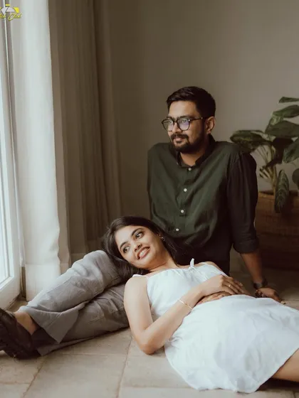 A relaxed and romantic pose by the window, with the bride-to-be resting her head on her partner's lap. The soft natural light creates a peaceful mood.