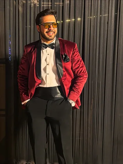 A confident stance, ready for the night. Dressed in a red tuxedo, I'm prepared to bring both style and substance to your Sangeet.