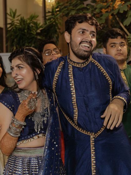 A candid moment of laughter, showcasing the intricate silver jewellery and the beautiful textures of the garba outfits.