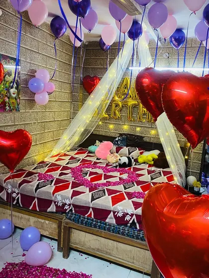 A closer look at the romantic birthday bedroom, showing the mix of latex and foil heart balloons and the delicate canopy over the bed.