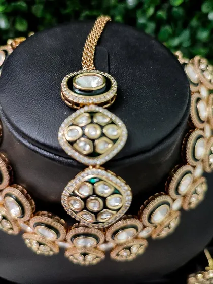 A close-up of the necklace and maang tikka, showing the beautiful black enamel outline that makes the kundan stones pop.
