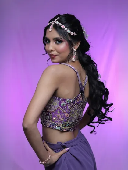 A portrait of a model with a creative hairstyle and a purple outfit, showcasing a modern glam look.