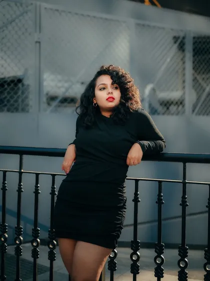 A portrait that plays with light and shadow on the street. The model's pose against the railing and the cool color palette create a sophisticated urban look.