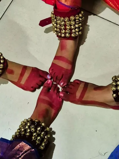 The sound of ghungroos (ankle bells) and the sight of feet adorned with alta (red dye) are fundamental to the Bharatanatyam tradition. This image symbolizes the coming together of our dancers in rhythm and unity.