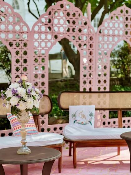 A stylish lounge area with pink jaali backdrops and modern-traditional furniture, creating a perfect blend of aesthetics for a Mehendi function.
