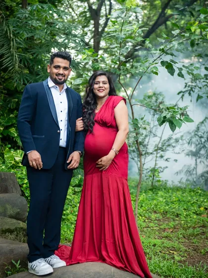 A classic couple portrait. They stand together, smiling, in a beautiful park, celebrating this special time in their lives.