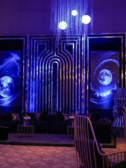 A view of the celestial lounge from the side, with the warm glow of candles contrasting with the cool blue light on the moon-themed backdrop.
