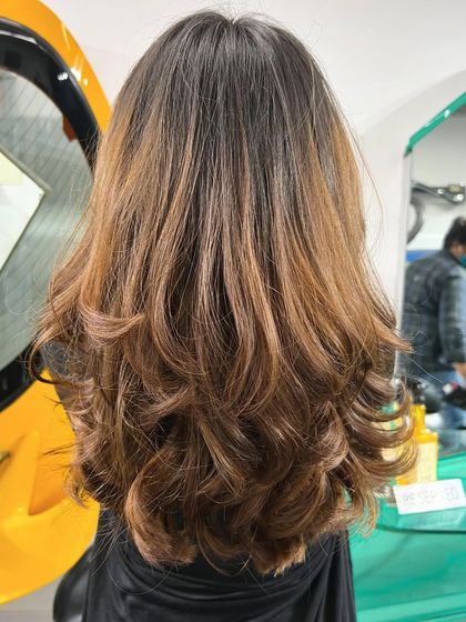 A still shot capturing the beautiful blend of this Honey Caramel Balayage. The curls at the end help to show off the different tones created during the colouring process.