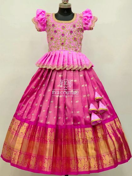 A full view of a stunning all-pink Banarasi lehenga. The peplum blouse has intricate gold embroidery, and the skirt has a wide, traditional border.
