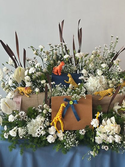 A sophisticated take on the jungle theme, this hamper combines wild animal figures with an elegant arrangement of white flowers and greenery.