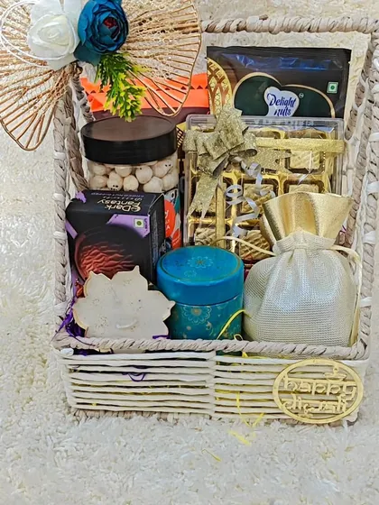 A premium woven basket hamper filled with goodies like Dark Fantasy cookies, makhanas, and a lotus diya.