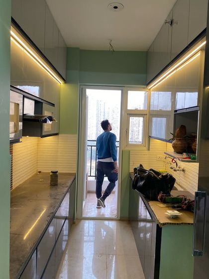 A look at a parallel kitchen during the final stages of installation. The profile lighting is on, highlighting the clean lines of the cabinets.