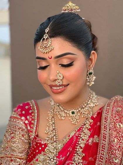 The elegance of a complete bridal set. This photo showcases a layered pearl and Polki necklace, a matching choker, intricate nose ring, and a delicate maang tikka, creating a truly unforgettable bridal profile.