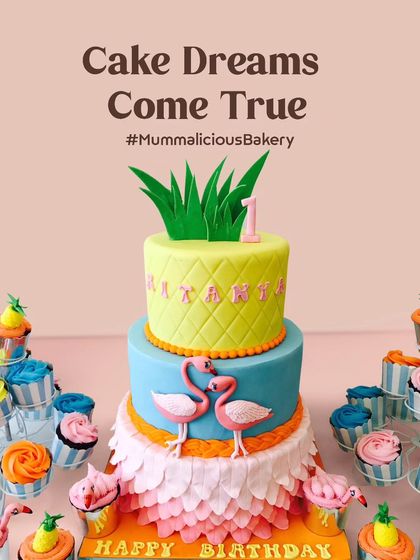 A tropical dream for a first birthday. This flamingo and pineapple themed cake, surrounded by colourful cupcakes, creates a vibrant and fun dessert table that's perfect for a summer celebration.