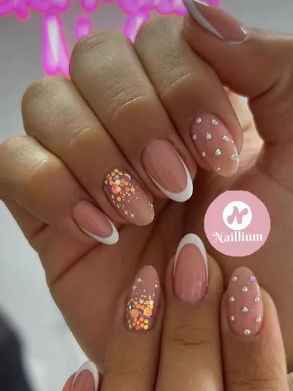 A sophisticated French manicure with rhinestone and confetti glitter accent nails.