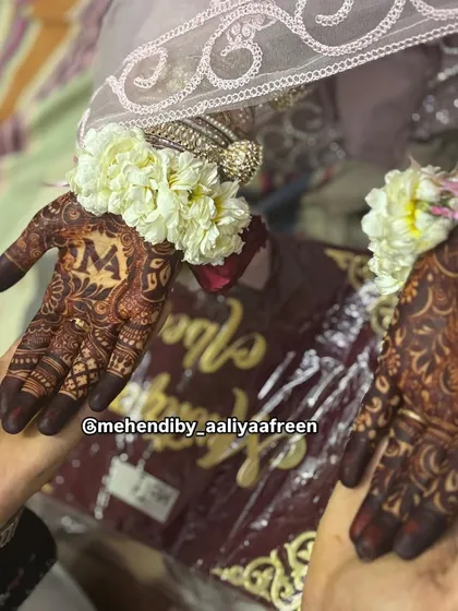 A close-up of the bride's hands, featuring the initial 'M' and intricate detailing on her wedding day.