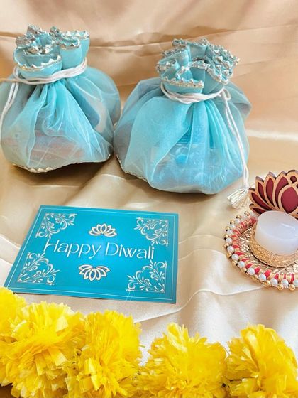 Elegant light blue potlis filled with goodies, paired with a Happy Diwali card and a lotus T-light holder. A simple and beautiful festive favor.