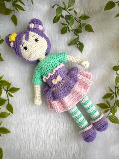 A beautiful doll with purple hair buns and a tutu dress. She also comes with a tiny backpack for her adventures. The striped stockings are attached, but her dress and shoes are removable.
